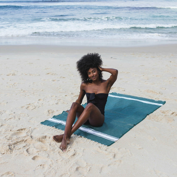 Femme allongée sur une fouta de plage couleur bleu canard - BY FOUTAS