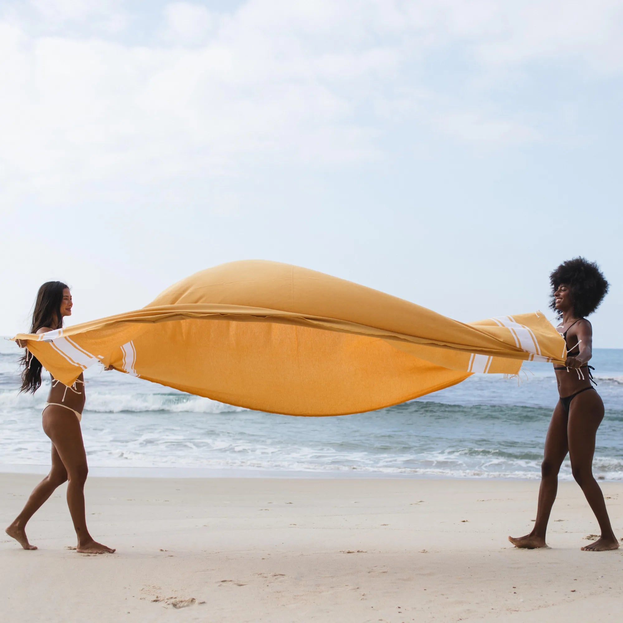 2 femmes étendent une fouta XXL sur le sol - BY FOUTAS