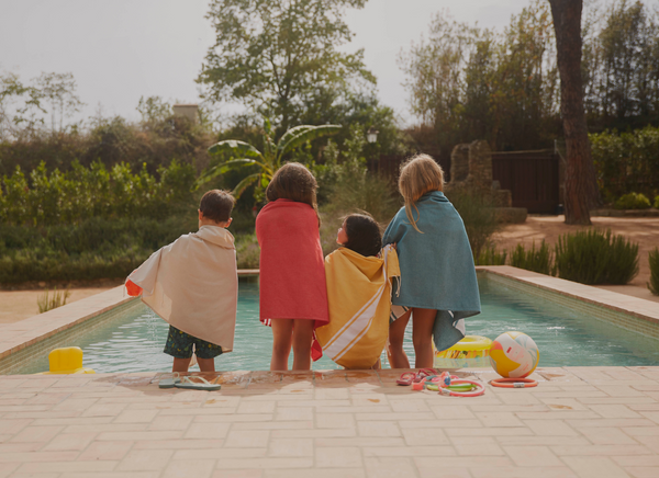 4 enfants au bord d'une piscine portant des foutas de plusieurs couleurs - BY FOUTAS