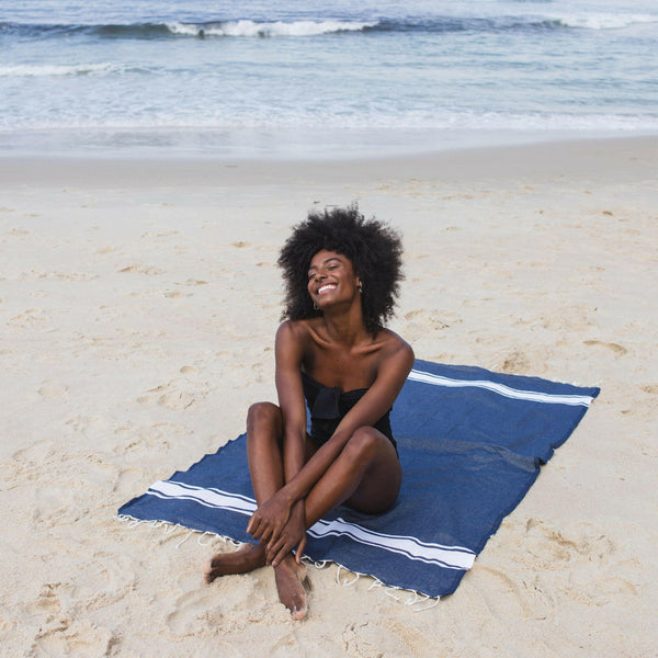 Woman lying on a navy blue beach fouta - BY FOUTAS