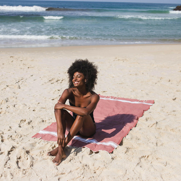 Woman lying on a powder pink beach fouta - BY FOUTAS