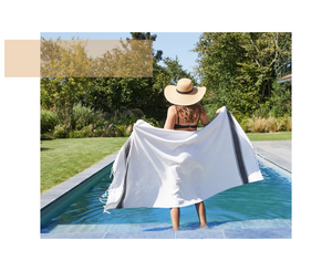 Frau vor einem Pool, die eine Saunatuch frottee  cyclades anthrazit offen hält