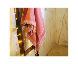fouta éponge unie rose poudrée accrochée sur une échelle dans une salle de bain