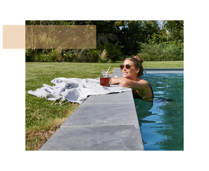 woman in a swimming pool with her arms resting on a grey fouta flat weave