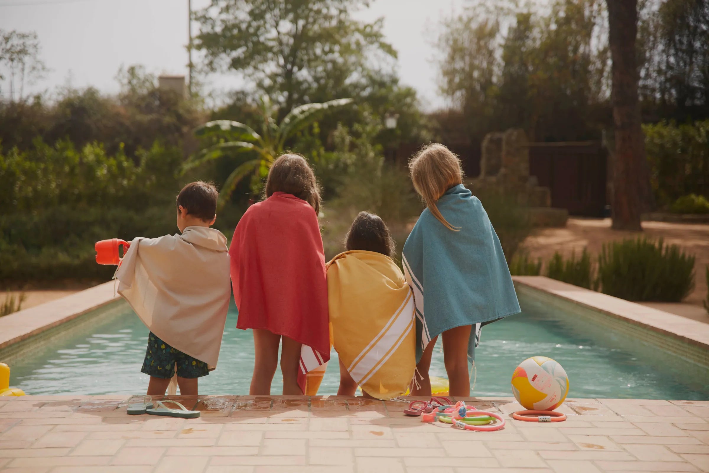 Enfants au bord d'une piscine avec des foutas sur le dos - BY FOUTAS