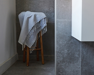 fouta éponge unie gris calcé posée sur un tabouret dans une salle de bain