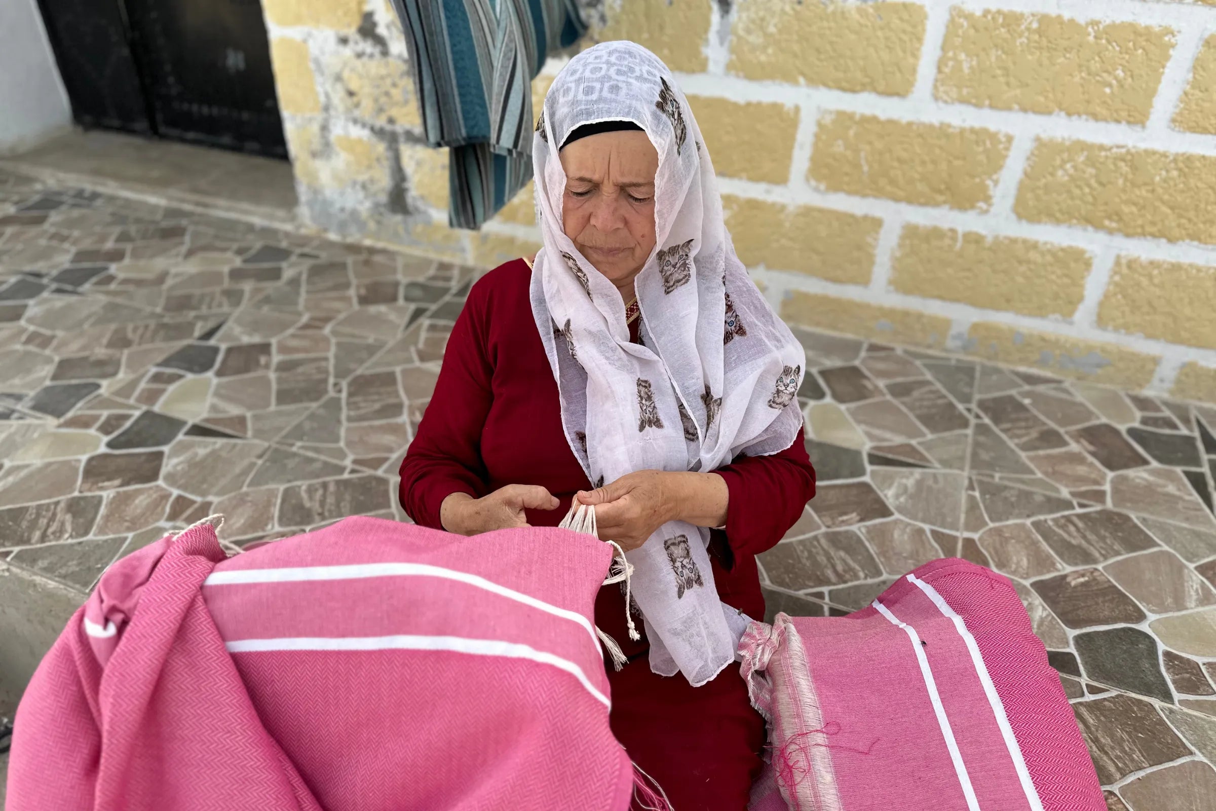 Woman tying the fringes of a fouta - BY FOUTAS