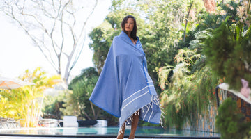 Mujer de pie delante de una piscina sosteniendo una fouta chevron - BY FOUTAS