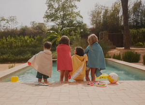 4 bambini accanto a una piscina che indossano foutas di vari colori - BY FOUTAS